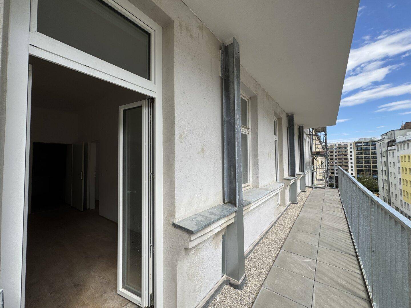 Langer, schmaler Balkon mit Metallgeländer und Blick auf die umliegenden Gebäude.
