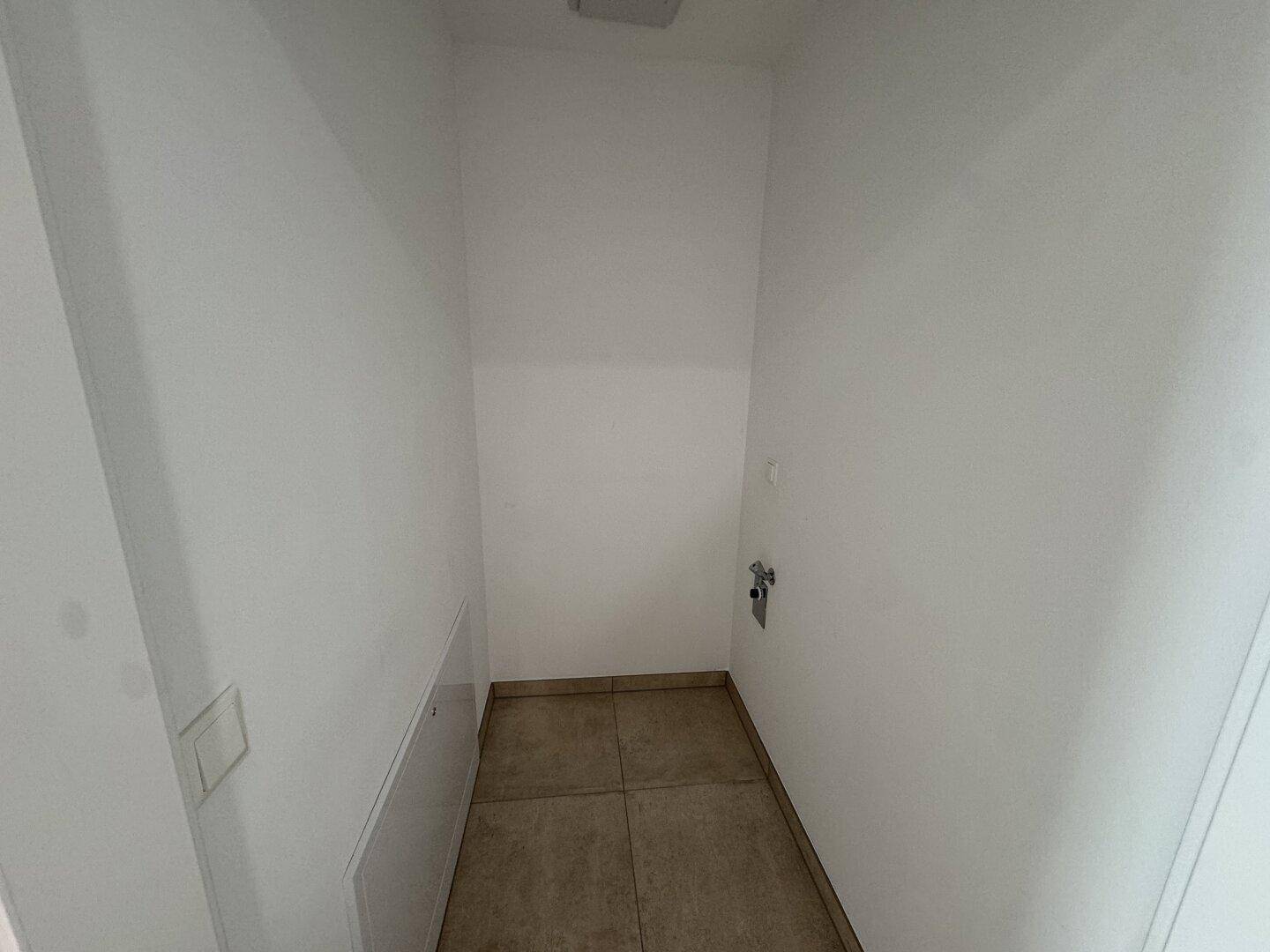 Praktischer Hauswirtschaftsraum mit Fliesenboden und Anschlüssen für Waschmaschine oder Trockner.
