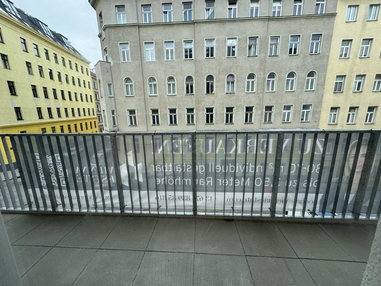 Balkon mit Metallgeländer und Blick auf die umliegenden Stadtgebäude.