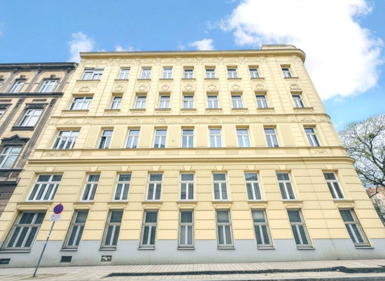 Breite Fassade eines historischen Gebäudes mit vielen Fenstern und gelbem Anstrich.