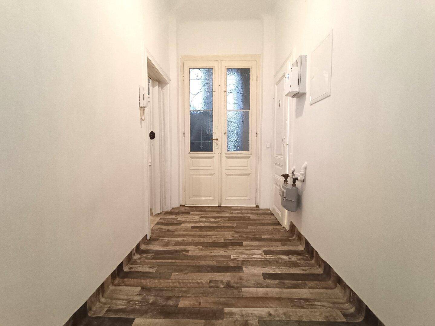 Eingangsbereich mit Holzlaminatboden und einer Doppeltür, die in die Wohnung führt.