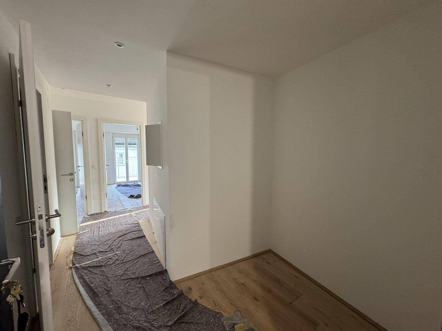 Flur mit Holzboden und Schutzabdeckung, der auf weitere Räume führt.