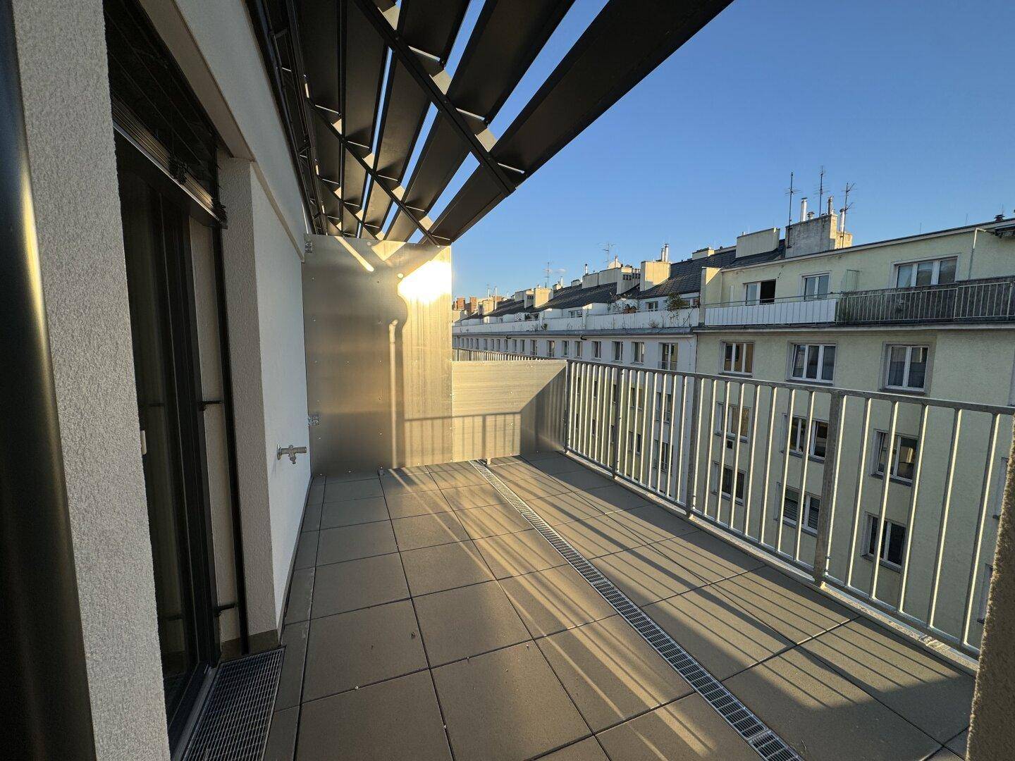 Geräumiger Balkon mit Fliesenboden und Blick auf die umliegenden Gebäude.
