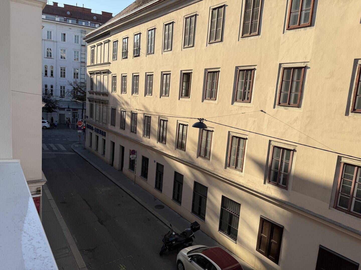 Blick von einem Balkon auf eine ruhige Stadtstraße mit historischen Gebäuden.