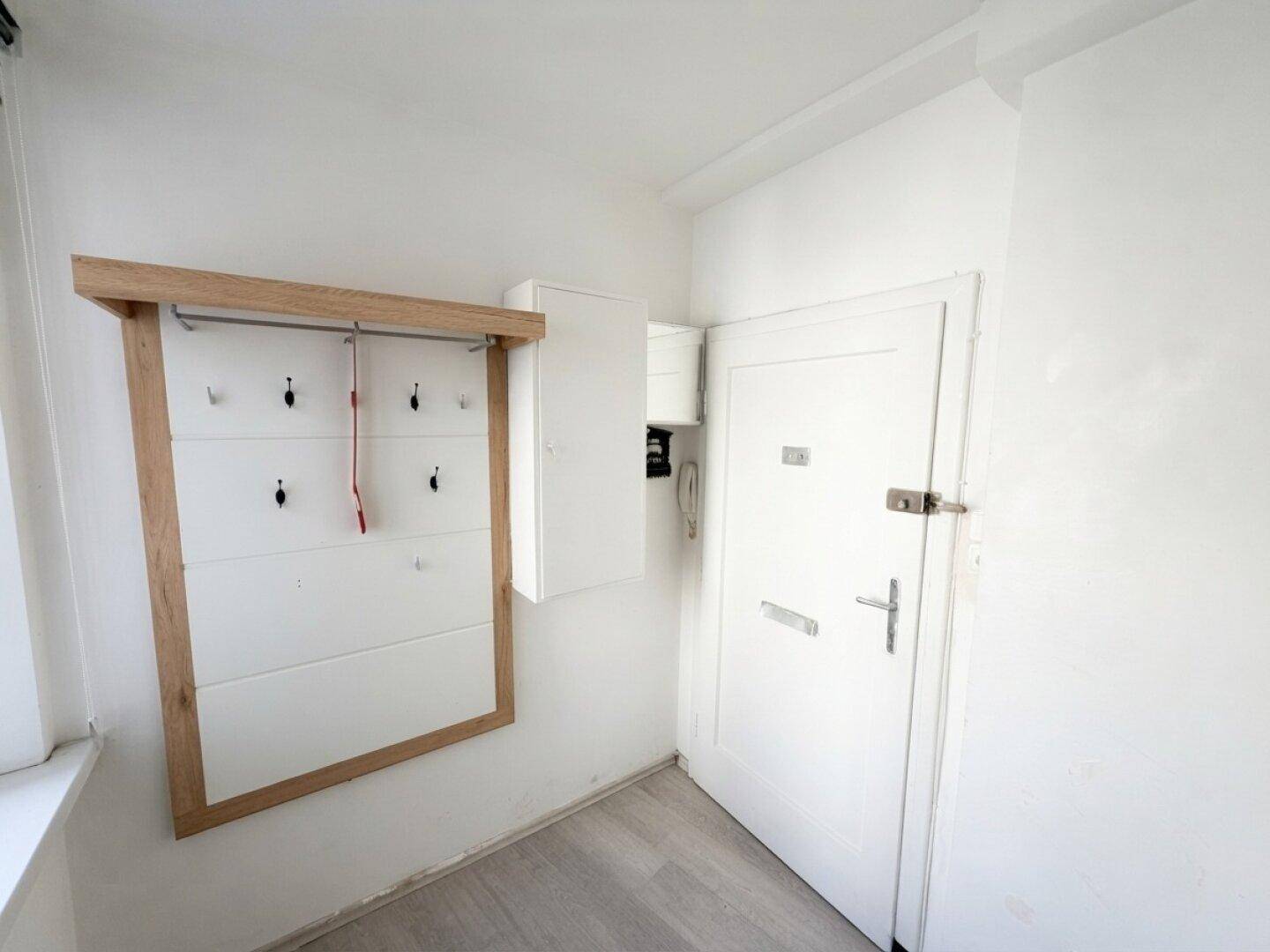 Eingangsbereich mit Garderobe, Gegensprechanlage und heller Holzlaminatboden.