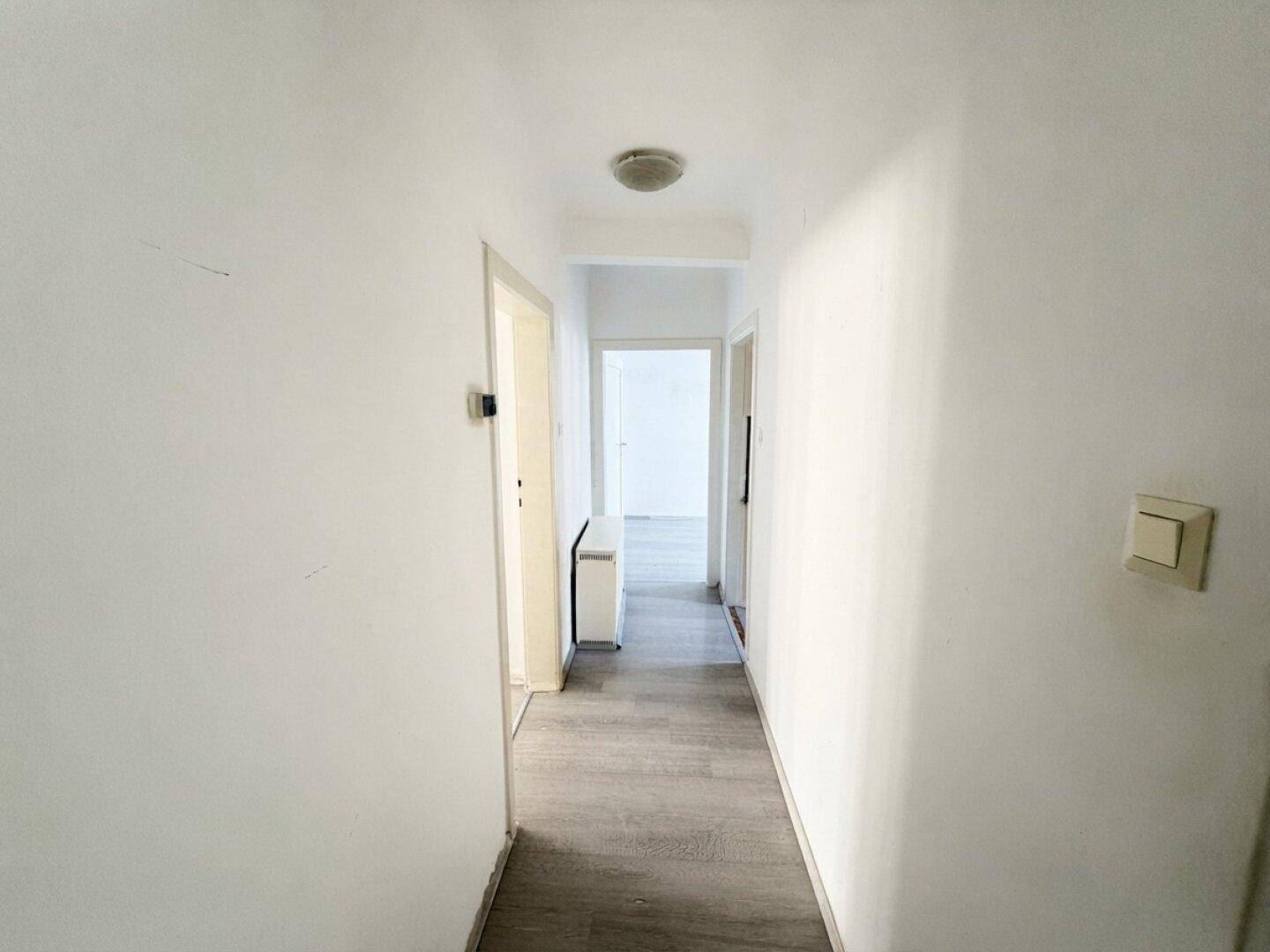 Heller Flur mit Laminatboden und Türen zu verschiedenen Zimmern der Wohnung.