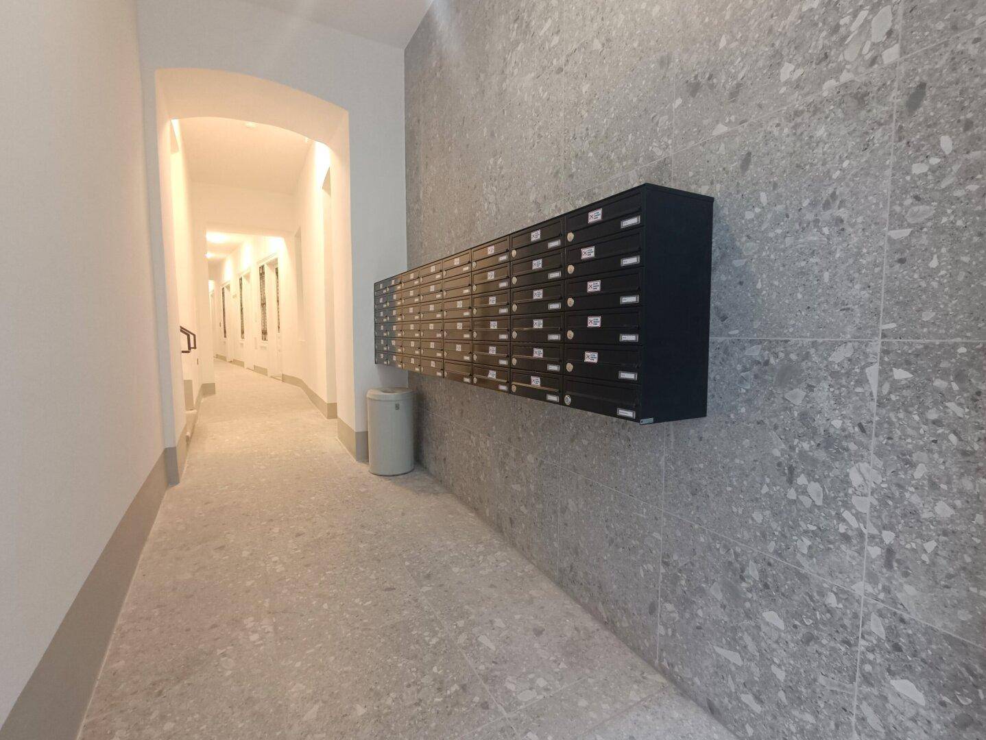 Heller Eingangsbereich mit modernen Fliesen und Briefkästen an der Wand.