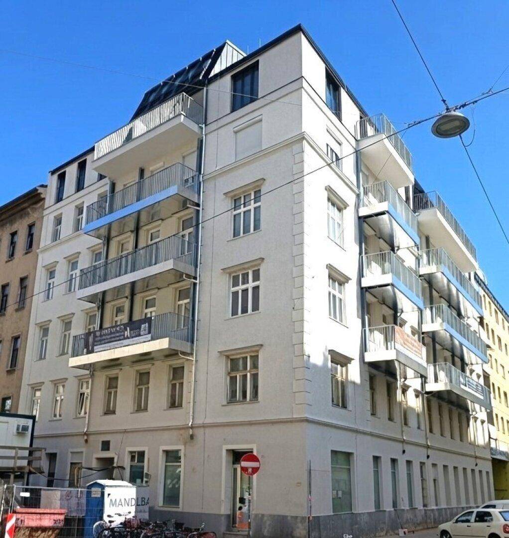 Modernisiertes Mehrfamilienhaus mit vielen Balkonen und blauen Geländern in der Stadt.