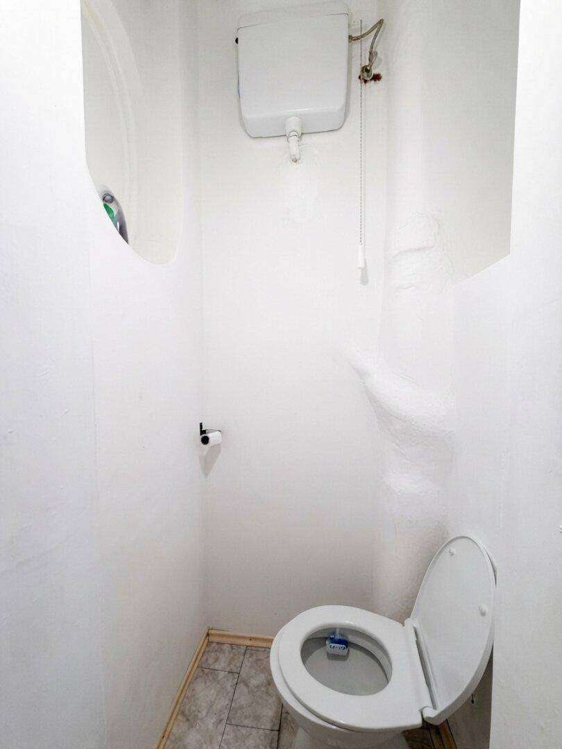 Kleines WC mit einfacher Toilette und Fliesenboden in einem schlichten Design.