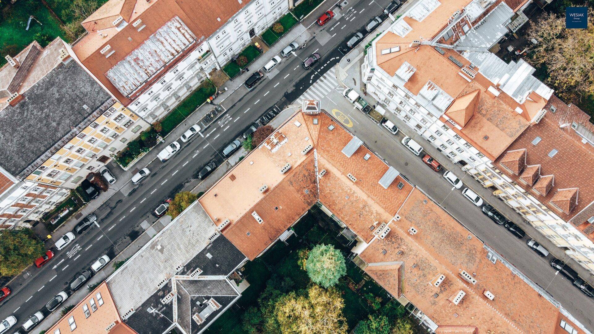 Draufsicht auf ein Stadtviertel mit Gebäuden, Straßen und parkenden Autos.