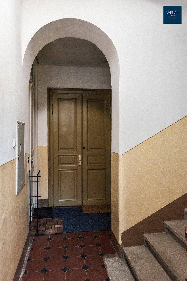 Treppenabsatz mit einer eleganten Bogenöffnung und einer klassischen Holztür.