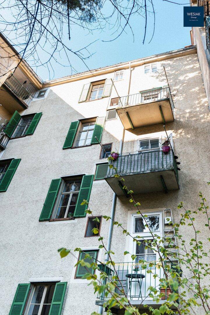 Fassade eines Wohngebäudes mit kleinen Balkonen und grünen Fensterläden.