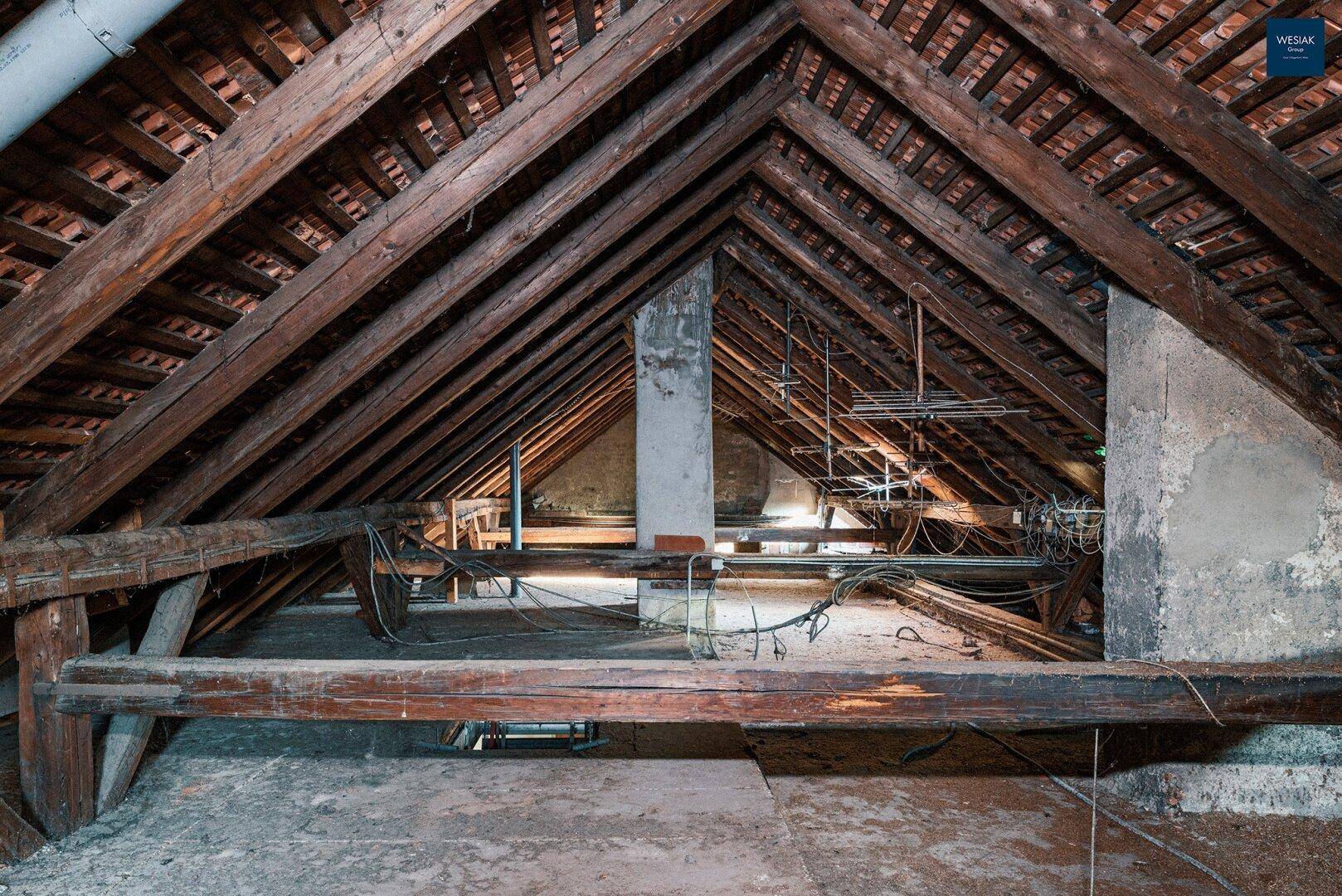 Dachboden mit robuster Holzkonstruktion und sichtbaren Dachsparren, bereit für Renovierung.