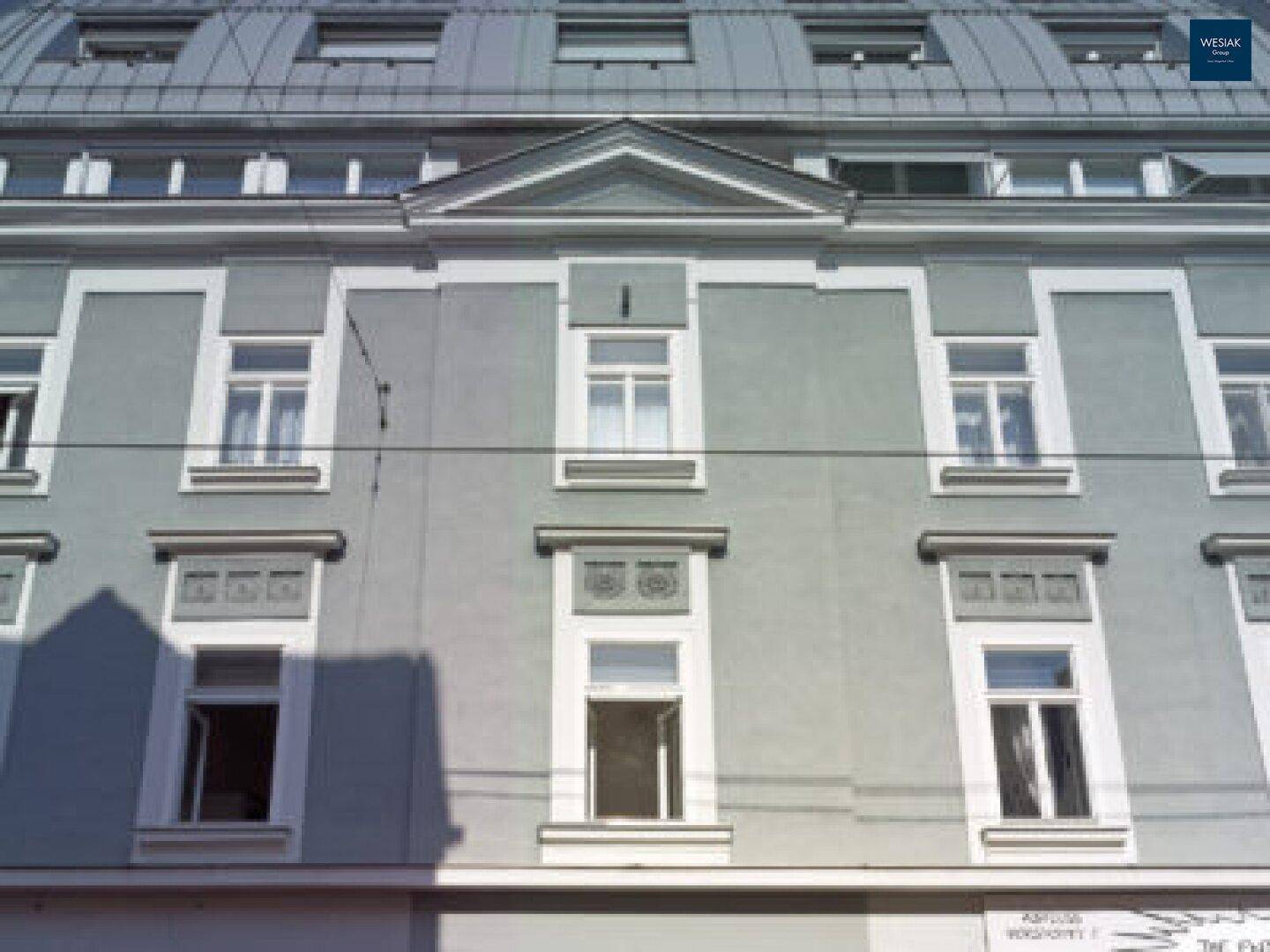 Historische Fassade eines Altbaus mit klassischen Fenstern und Verzierungen.
