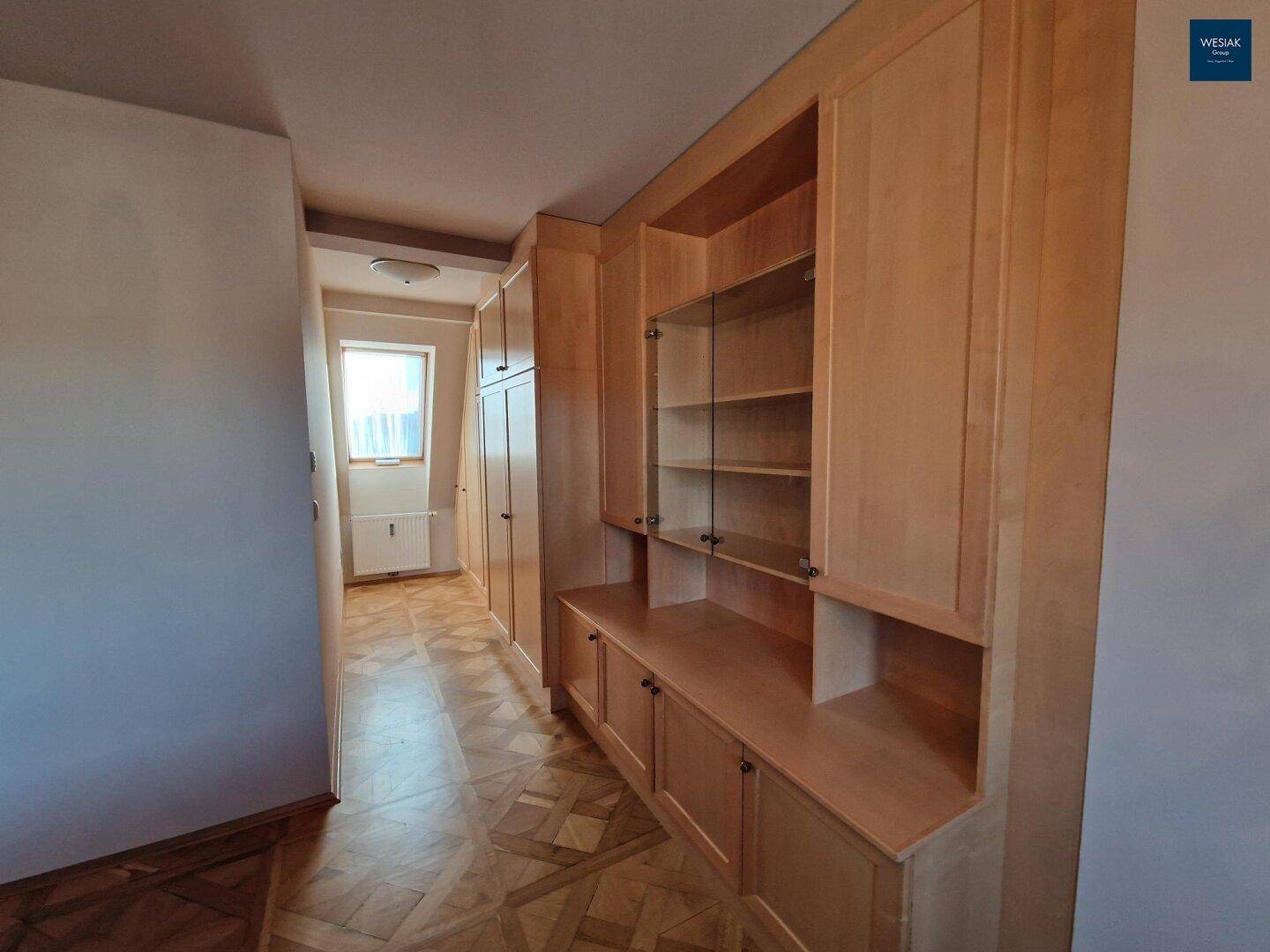 Heller Flur mit maßgefertigten Holzschränken und dekorativem Parkettboden.