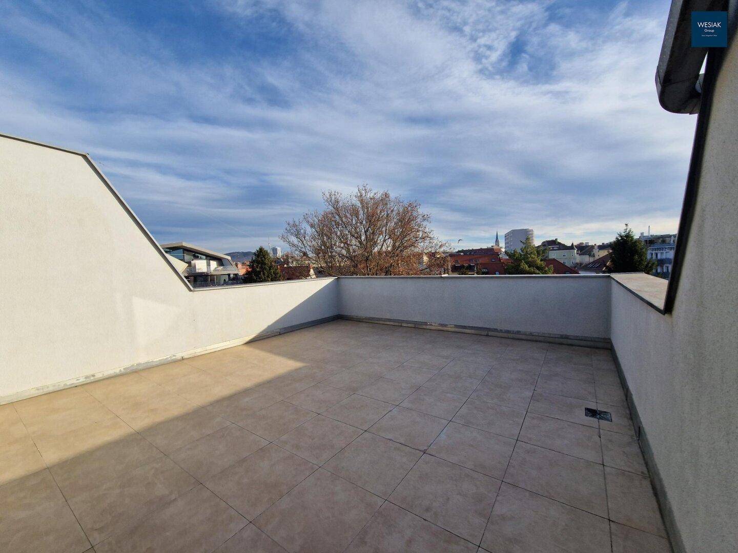 Weitläufige Dachterrasse mit hellen Fliesen und Blick über die umliegenden Dächer.