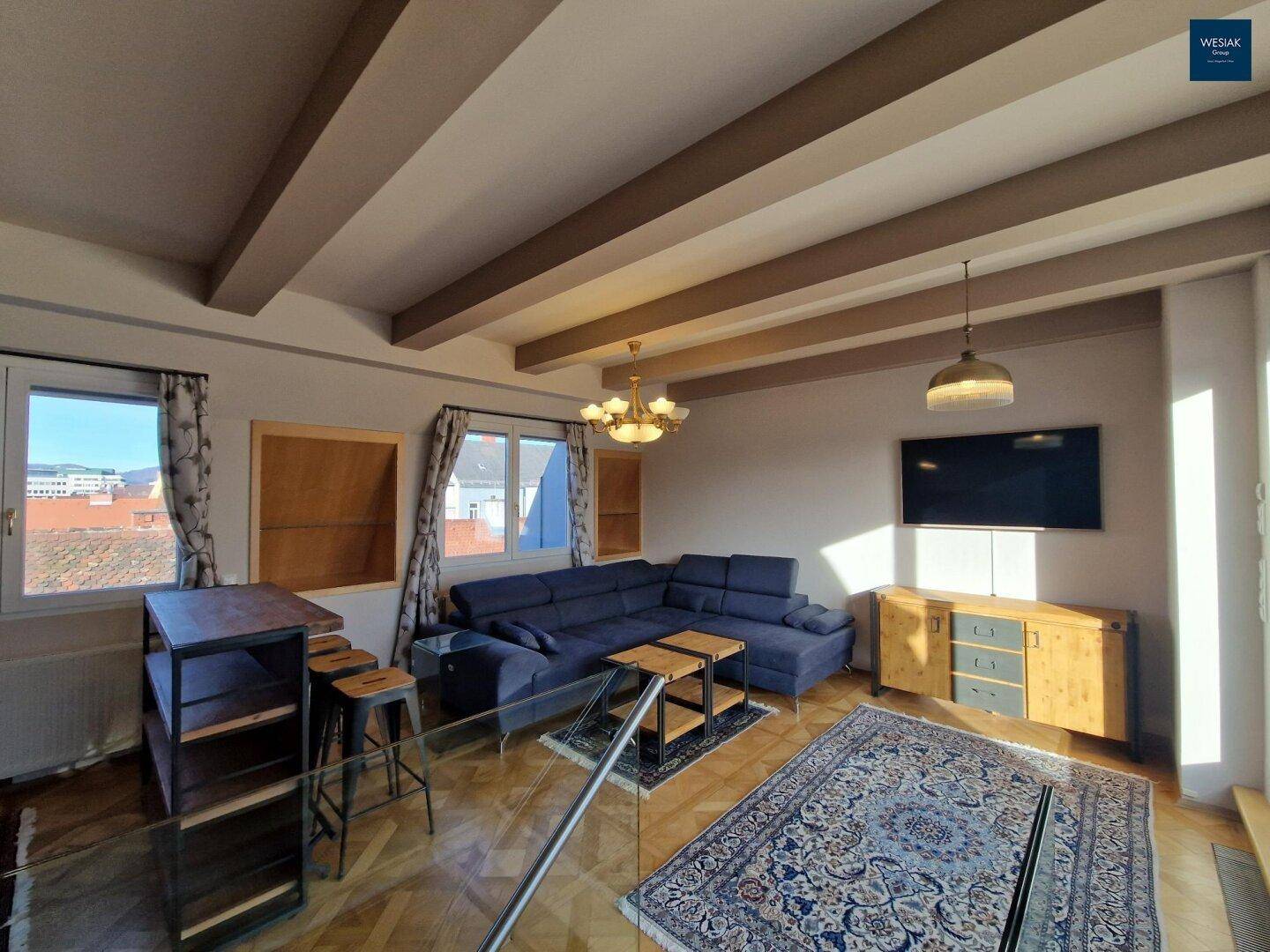 Geräumiger Wohnbereich mit großem Sofa, Fernseher und Blick auf die Stadt.