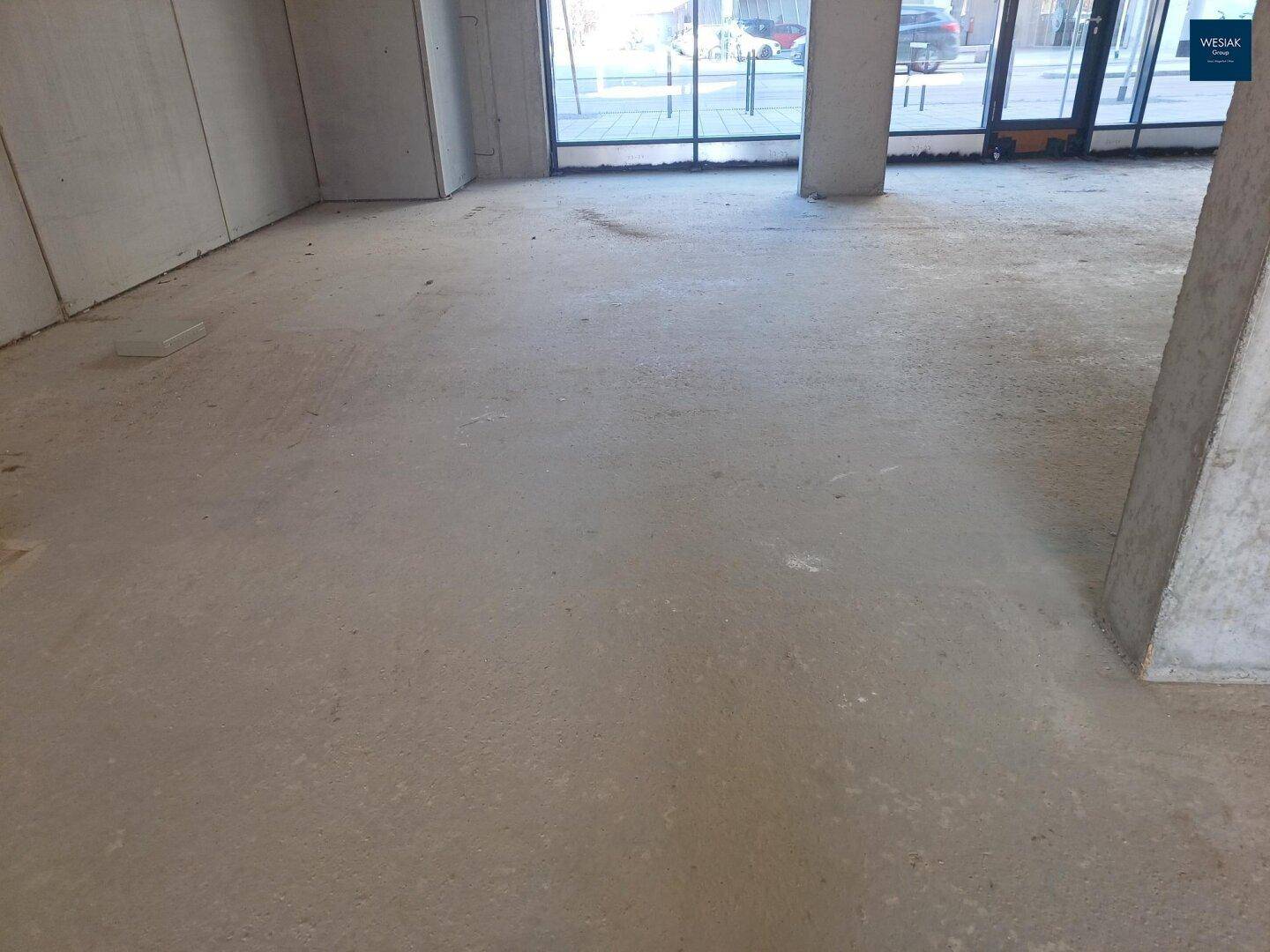 Nahaufnahme des Betonbodens in einem unfertigen Gewerberaum, der auf weitere Ausbauarbeiten wartet.