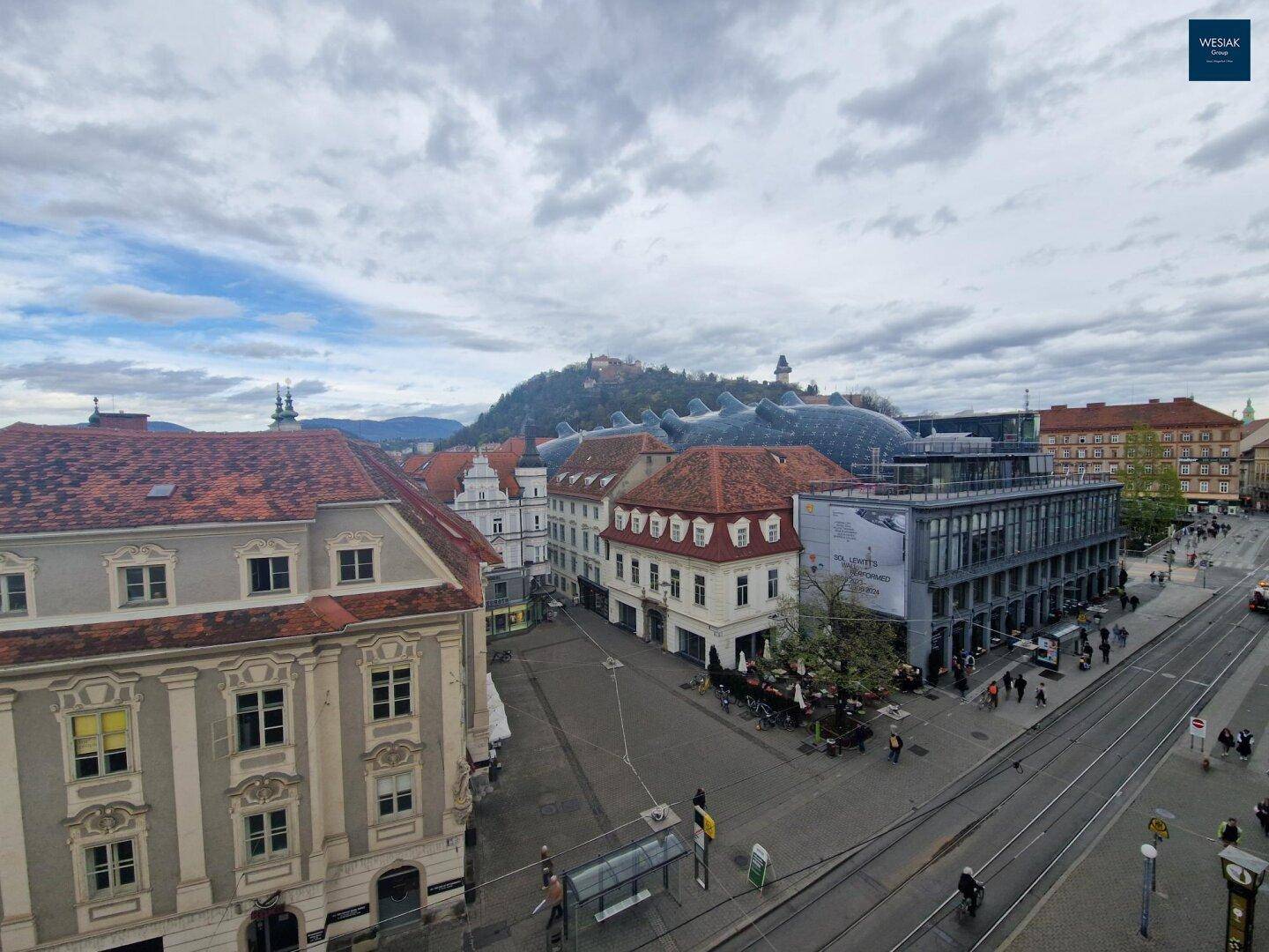 Panoramablick über die Stadt mit historischen Gebäuden und einem Berg im Hintergrund.