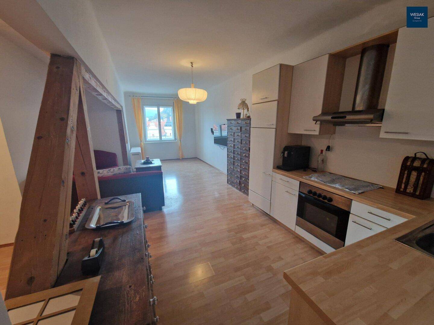 Heller Wohn-Essbereich mit integrierter Küche, Holzboden und Fenster mit Ausblick.
