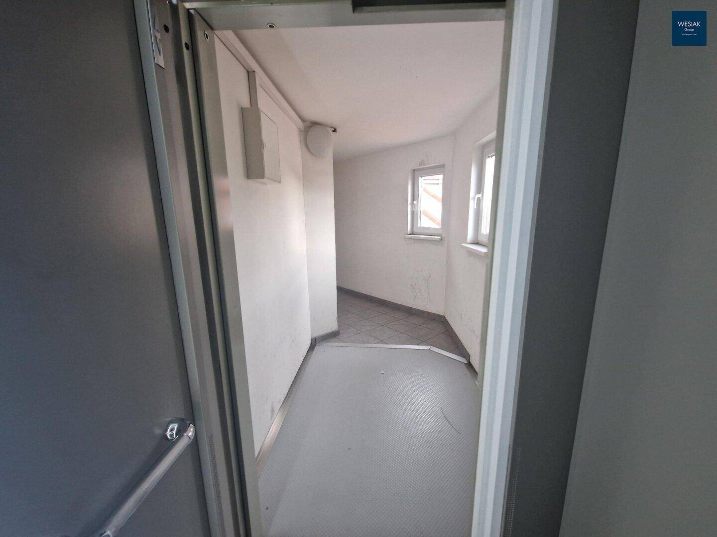 Heller Flur mit Fliesenboden und Fenstern, die Tageslicht hereinlassen.
