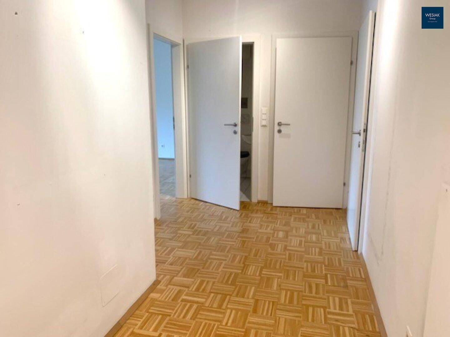 Heller Flur mit Parkettboden und mehreren Türen zu angrenzenden Räumen.