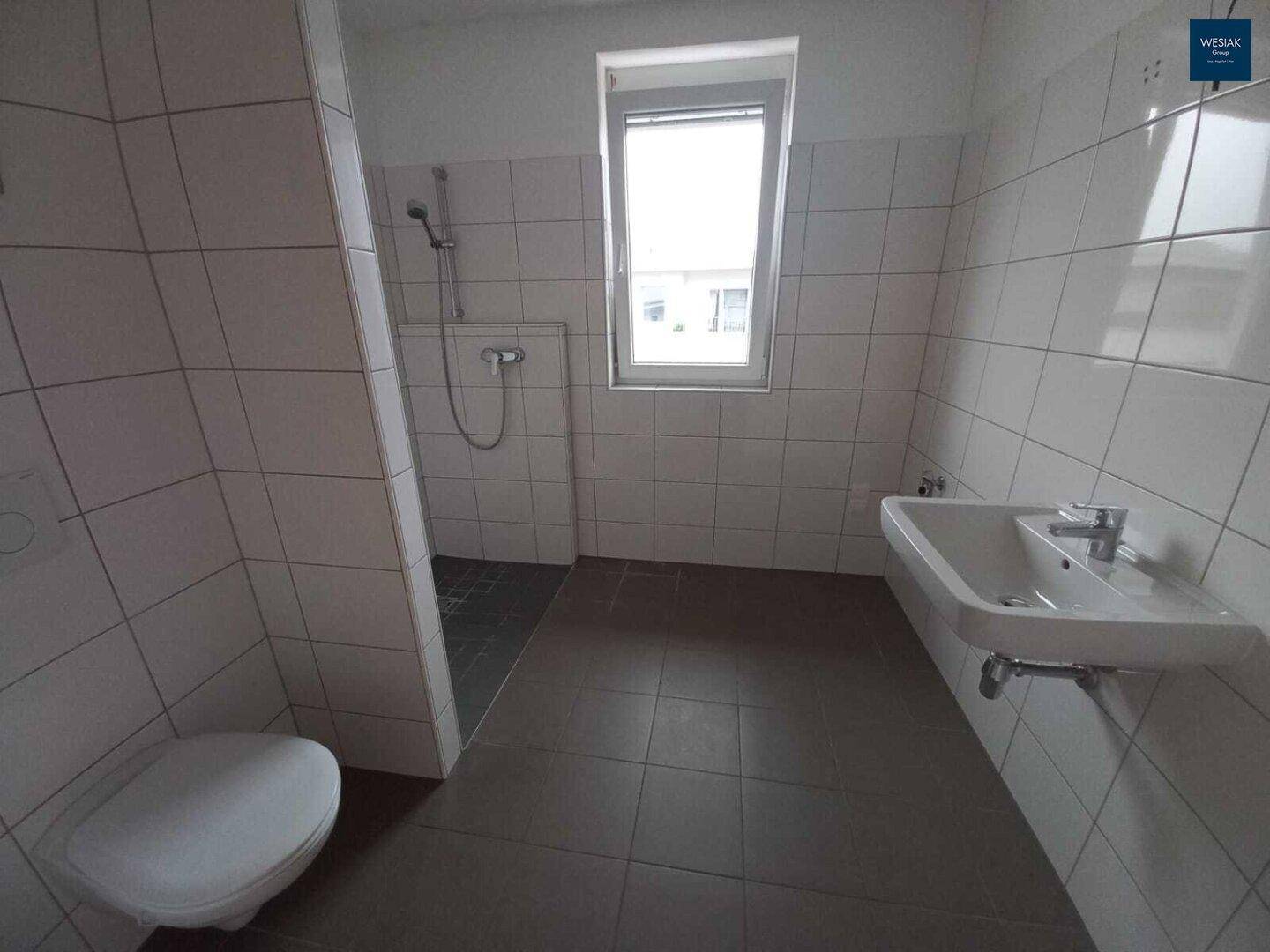 Helles Badezimmer mit Dusche, WC, Waschbecken und Fenster, in gutem Zustand.
