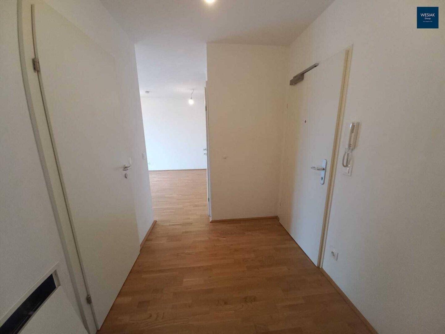 Eingangsbereich der Wohnung mit hellem Parkettboden und weiß gestrichenen Wänden.
