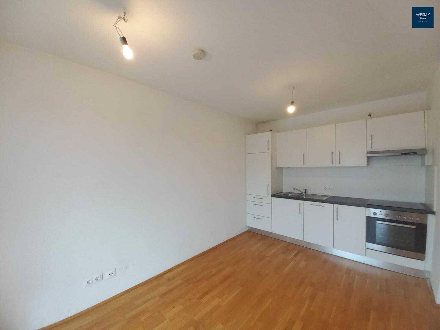 Wohnbereich mit moderner Küchenzeile, Parkettboden und viel Platz für Möbel.