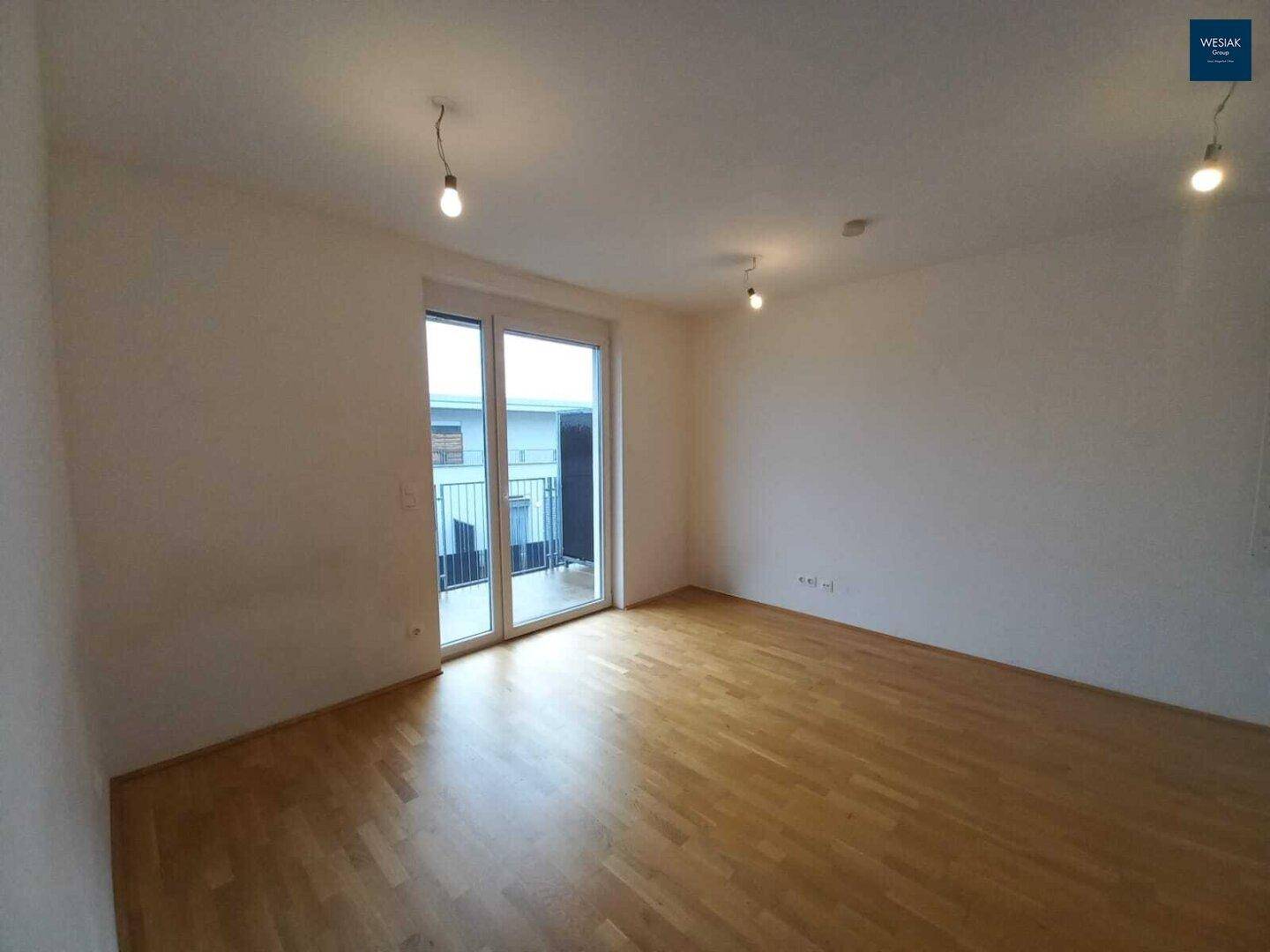 Heller Raum mit Parkettboden und Balkonzugang, bietet viel natürliches Licht.