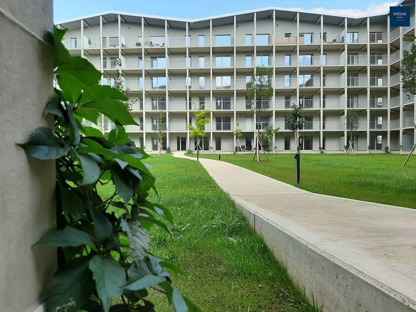 Moderne Wohnanlage mit ansprechender Architektur und gepflegtem Grünbereich im Innenhof.