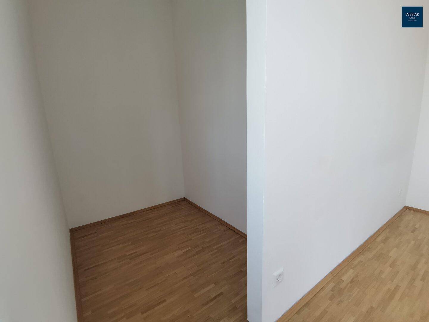 Kleiner, leerer Abstellraum oder begehbarer Schrank mit Parkettboden.