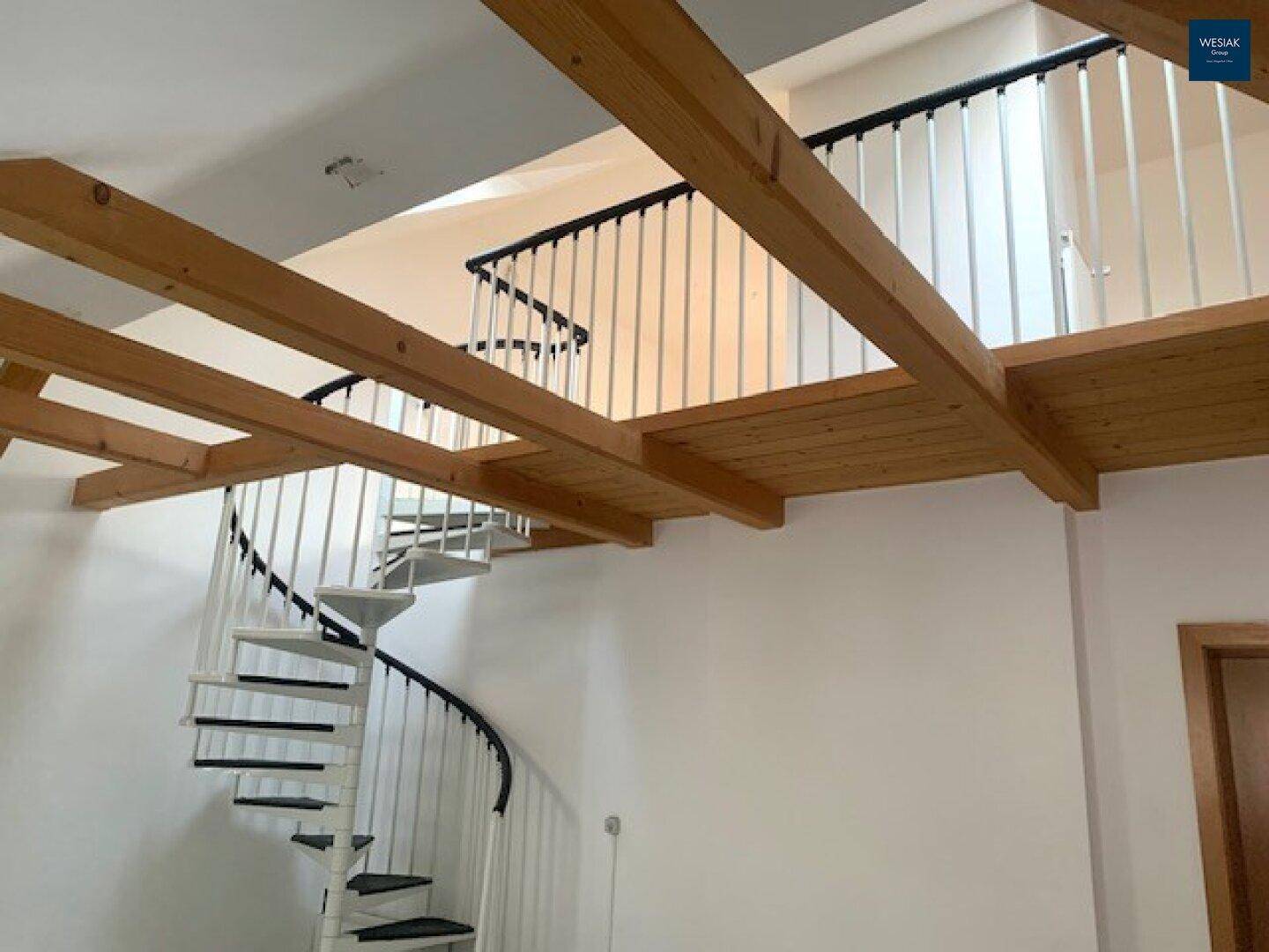 Geräumiger Wohnbereich mit offener Galerie, Holzbalken und Wendeltreppe.