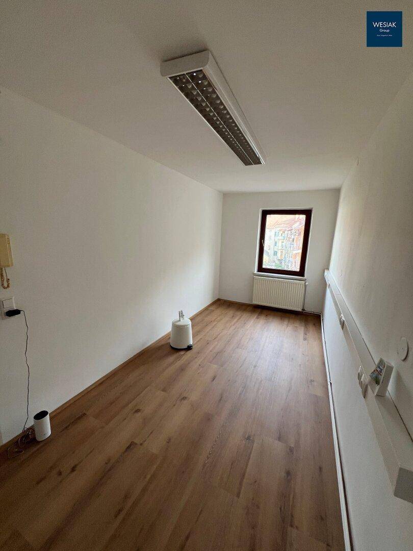Leeres Büro mit hellem Holzfußboden und Fenster, bereit zur individuellen Gestaltung.
