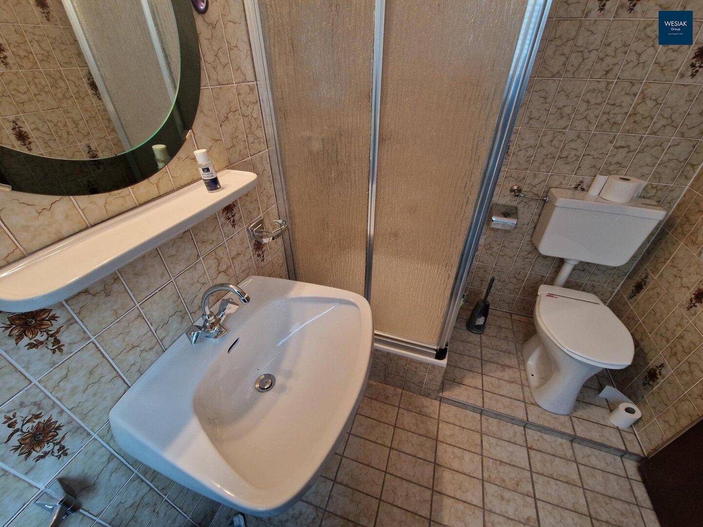 Kleines Badezimmer mit Waschbecken, Toilette und Duschkabine, komplett gefliest in einem traditionellen Stil.