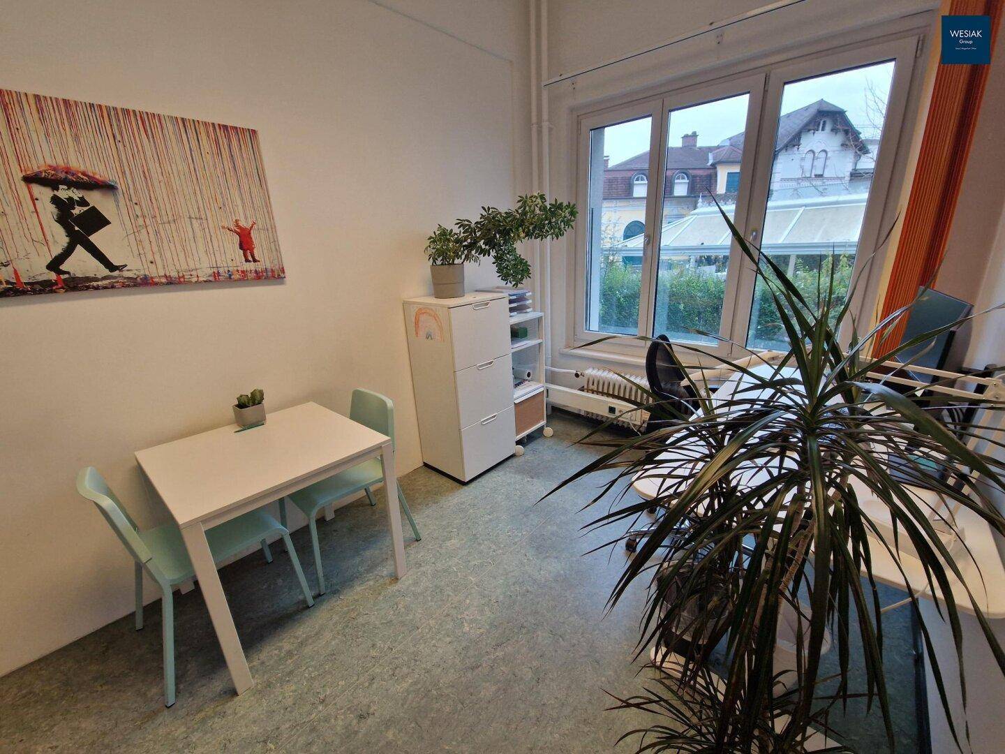 Heller Bürobereich mit kleinem Tisch, Stühlen und Blick auf die Umgebung.