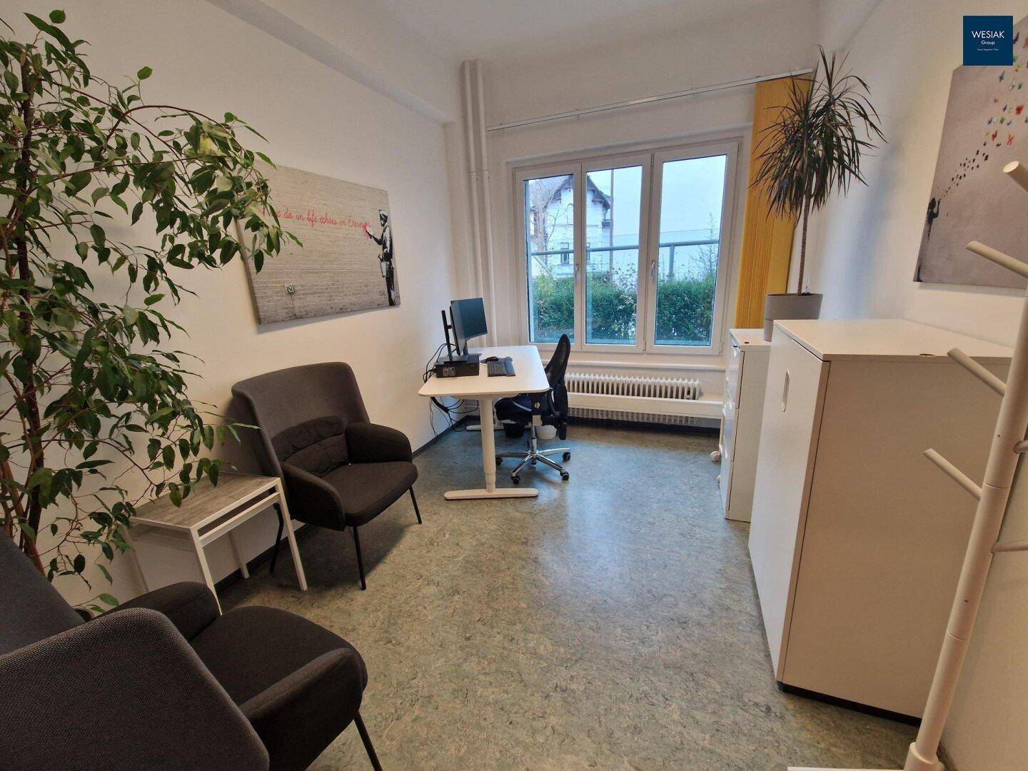 Helles Büro mit Schreibtisch, bequemen Sesseln und Blick ins Grüne.