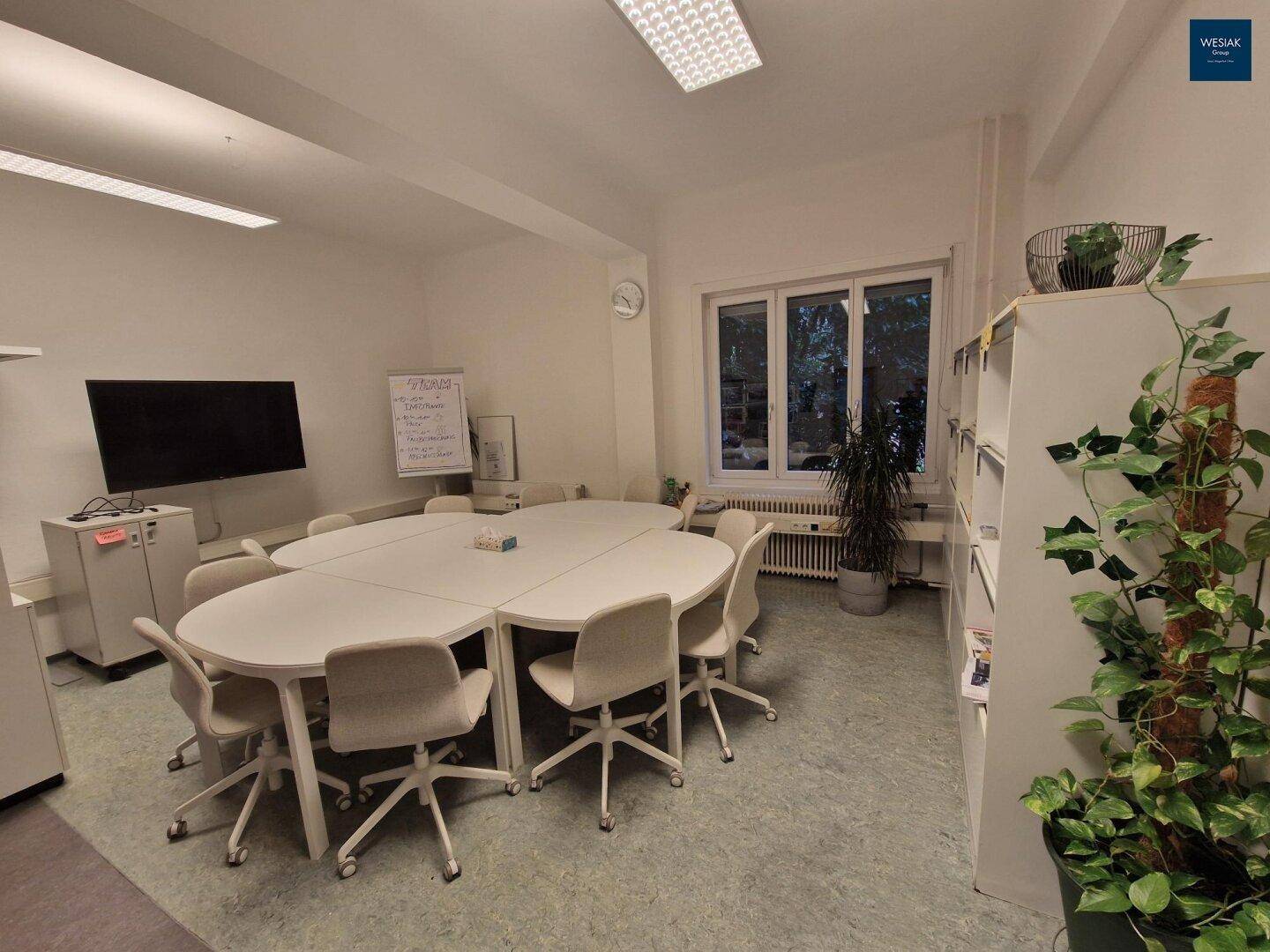 Geräumiger Konferenzraum mit großem ovalen Tisch, Bürostühlen und Blick ins Grüne.