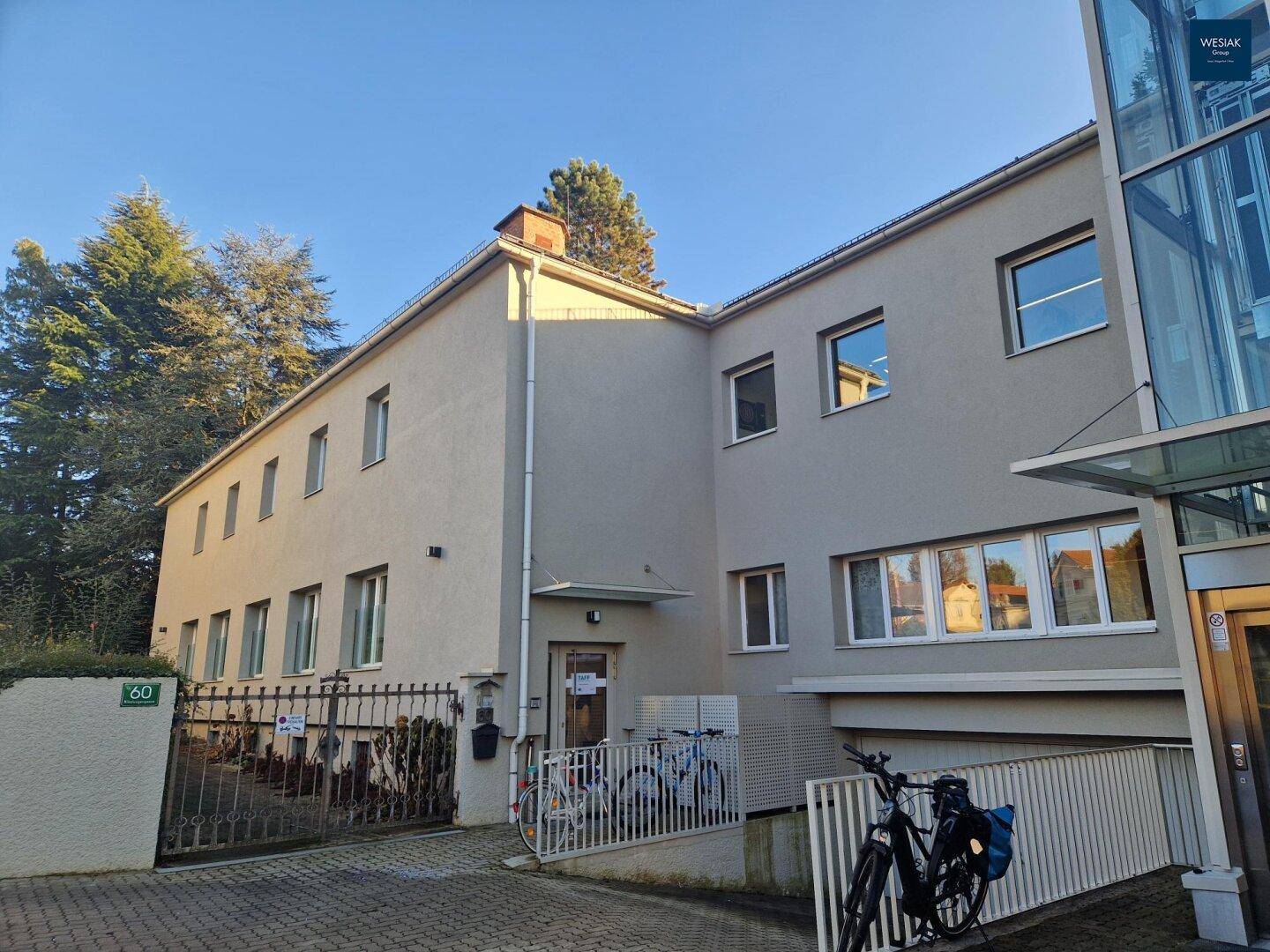 Ansicht des Gebäudes mit Eingangsbereich, Garagenzufahrt und externem Glasaufzug.