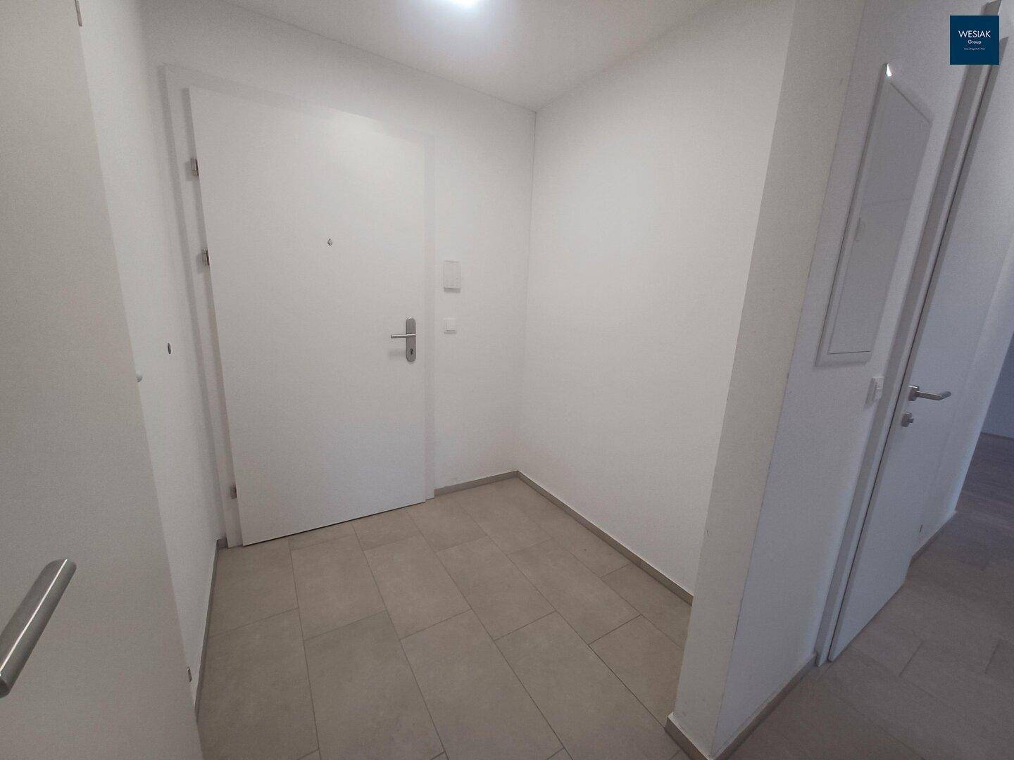 Heller Eingangsbereich mit Fliesenboden und weiß gestrichenen Wänden.
