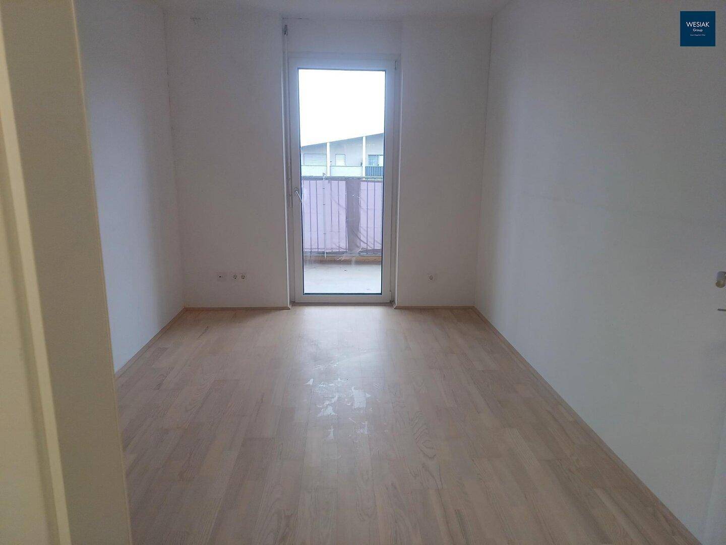 Geräumiges Schlafzimmer mit hellem Holzboden und direktem Zugang zum Außenbereich.