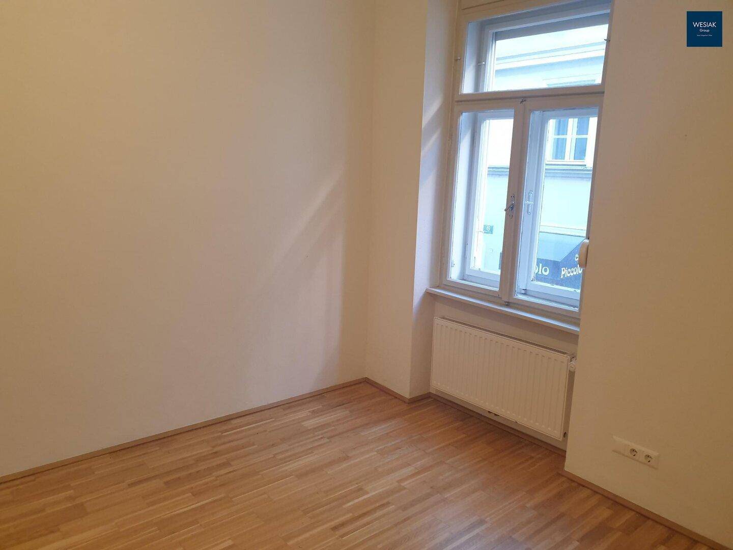 Helles Zimmer mit Parkettboden und Fenster zur Straße, bietet eine gute Belichtung.