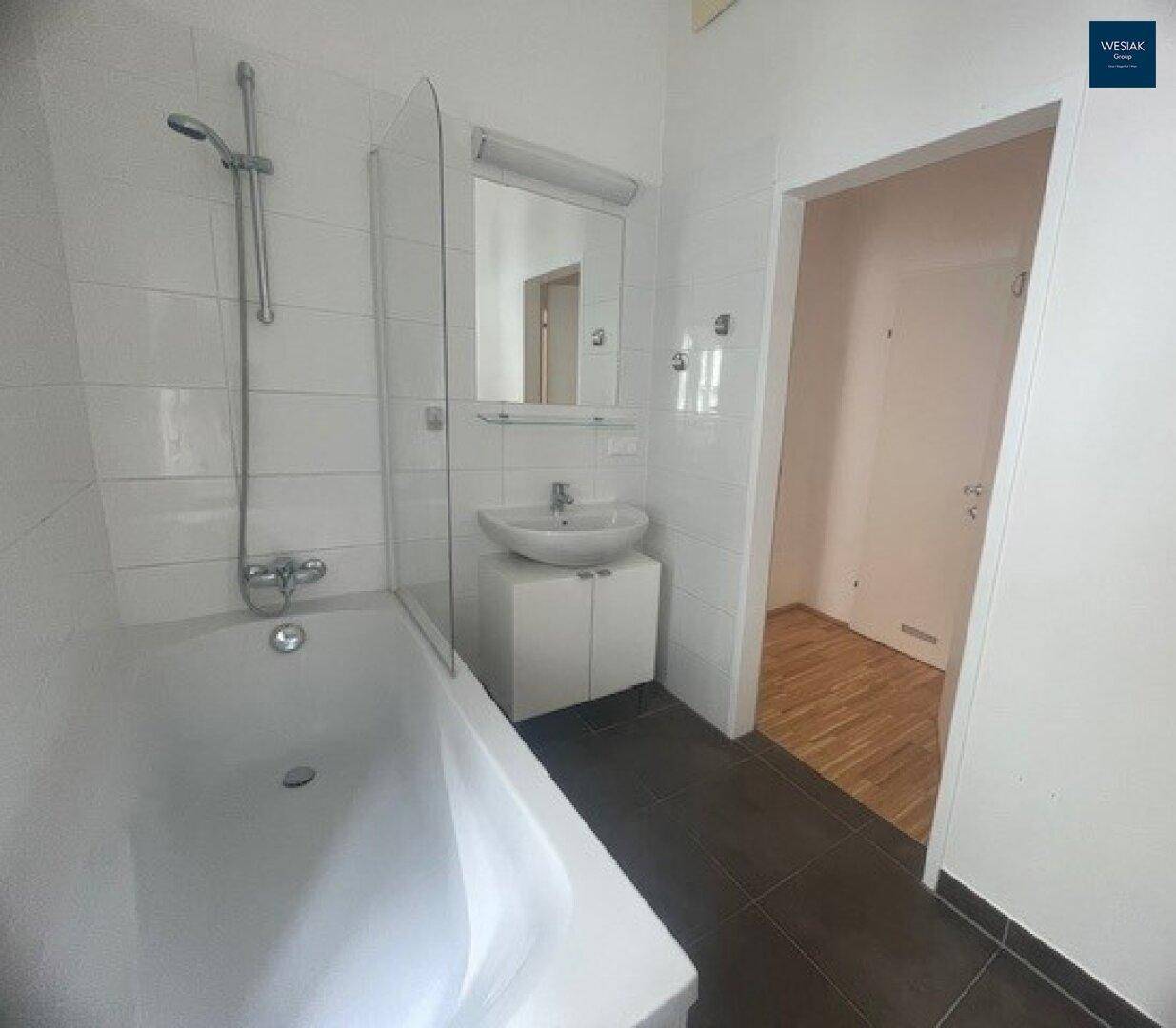 Modernes Badezimmer mit Badewanne, Duschvorrichtung und stilvollem Waschbecken, gut gepflegt.