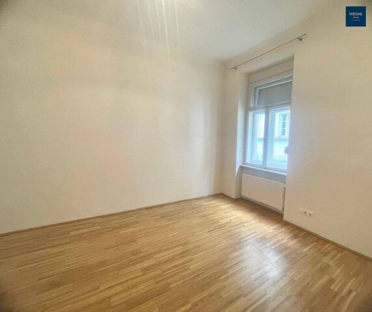 Ruhiges Zimmer mit Parkettboden und einem Fenster, ideal als Schlaf- oder Arbeitszimmer.
