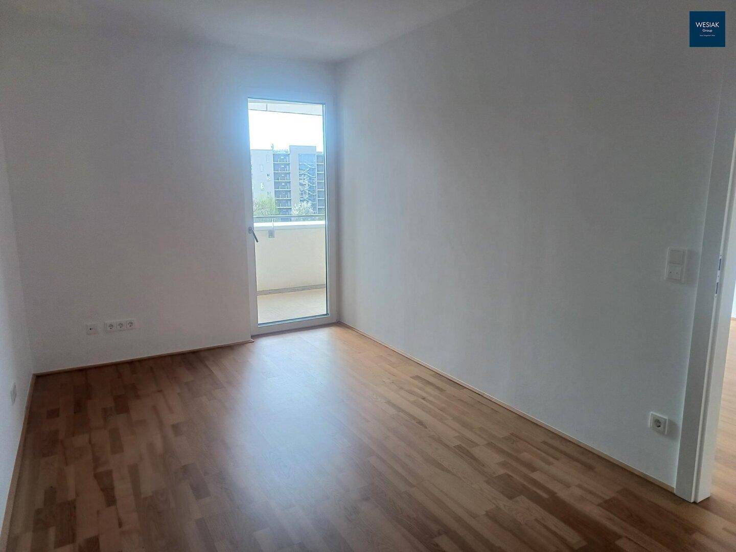 Helles Schlafzimmer mit Holzboden und direktem Zugang zu einem Balkon.
