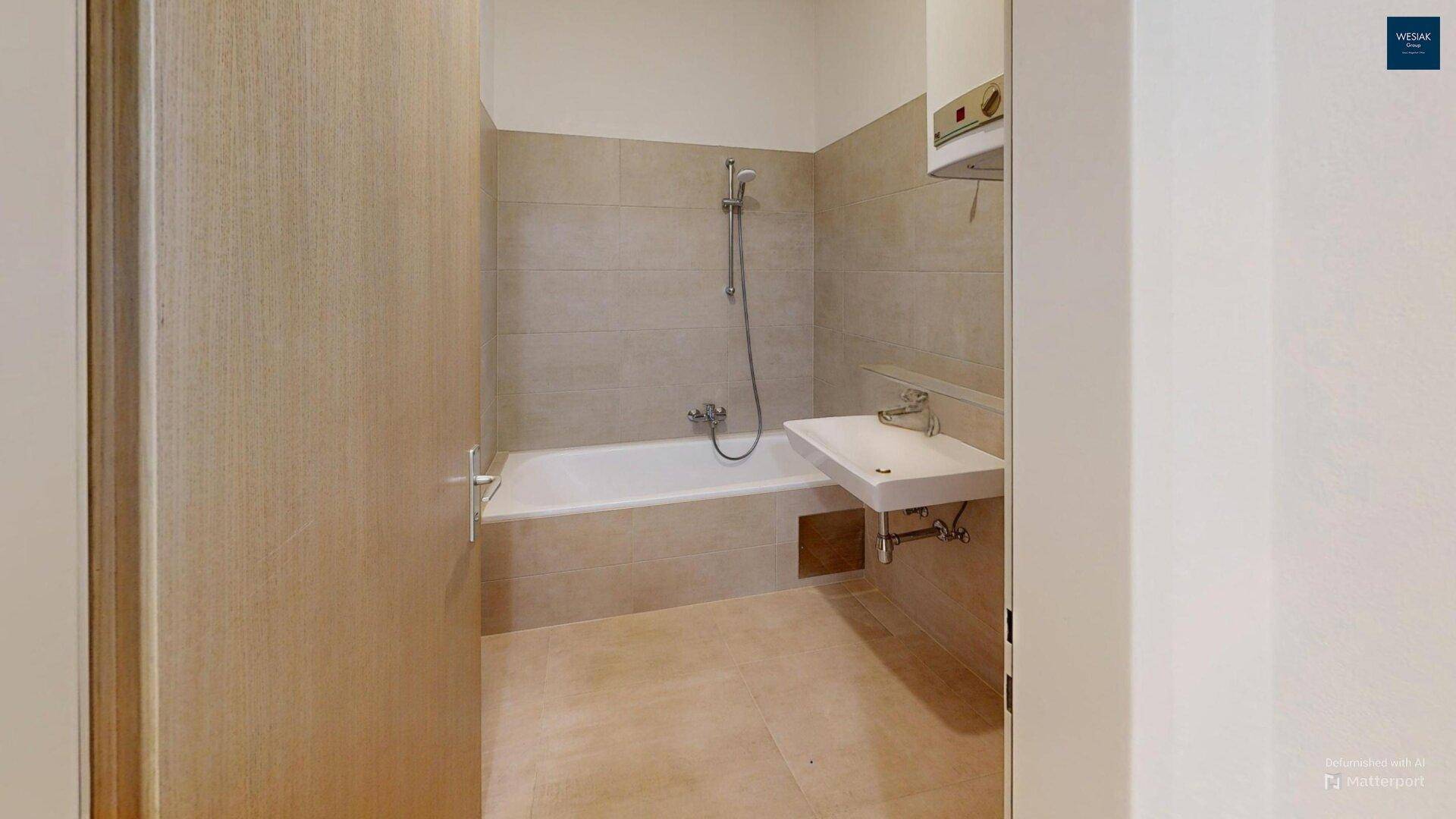 Badezimmer mit Badewanne, Waschbecken und hellen Fliesen.