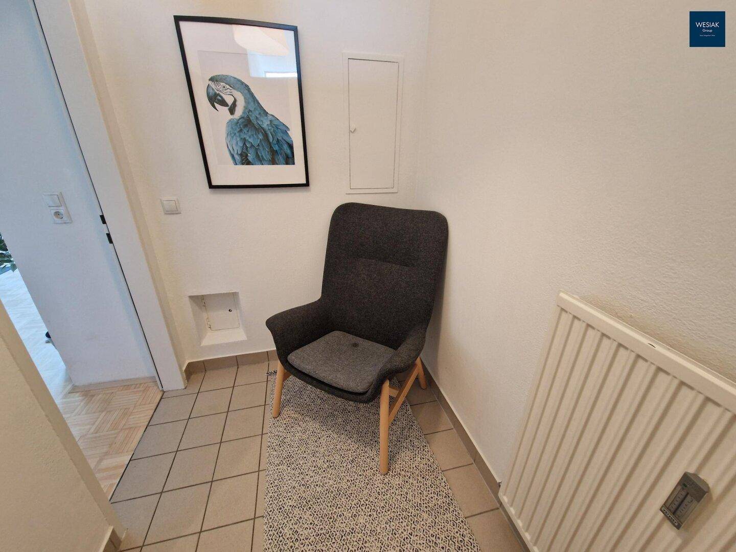 Eingangsbereich mit Fliesenboden, Sessel und Heizkörper.