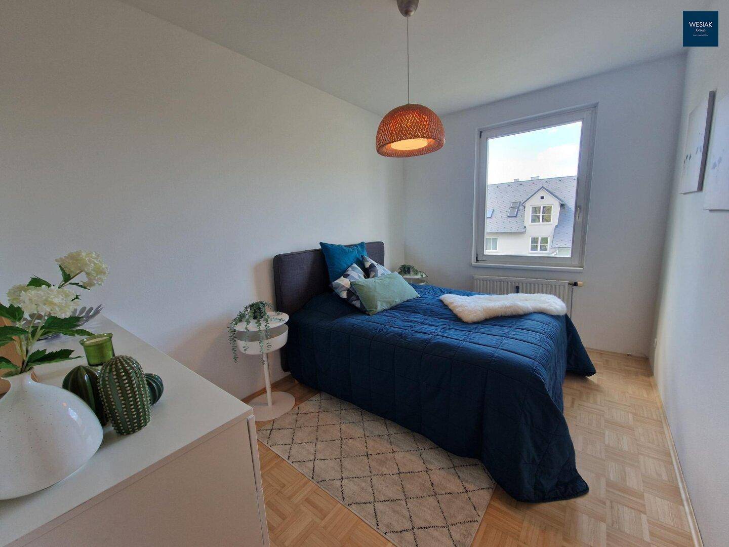 Schlafzimmer mit Doppelbett, Parkettboden und Fenster mit Blick auf die Nachbarschaft.