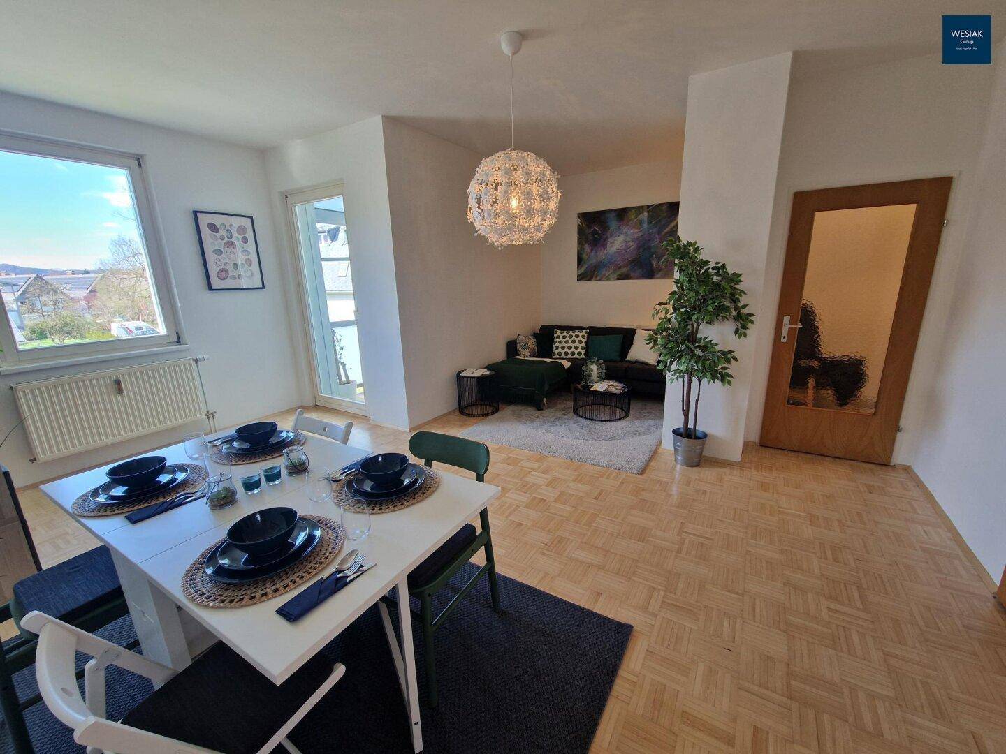 Geräumiger Wohn- und Essbereich mit Parkettboden und Zugang zum Balkon.