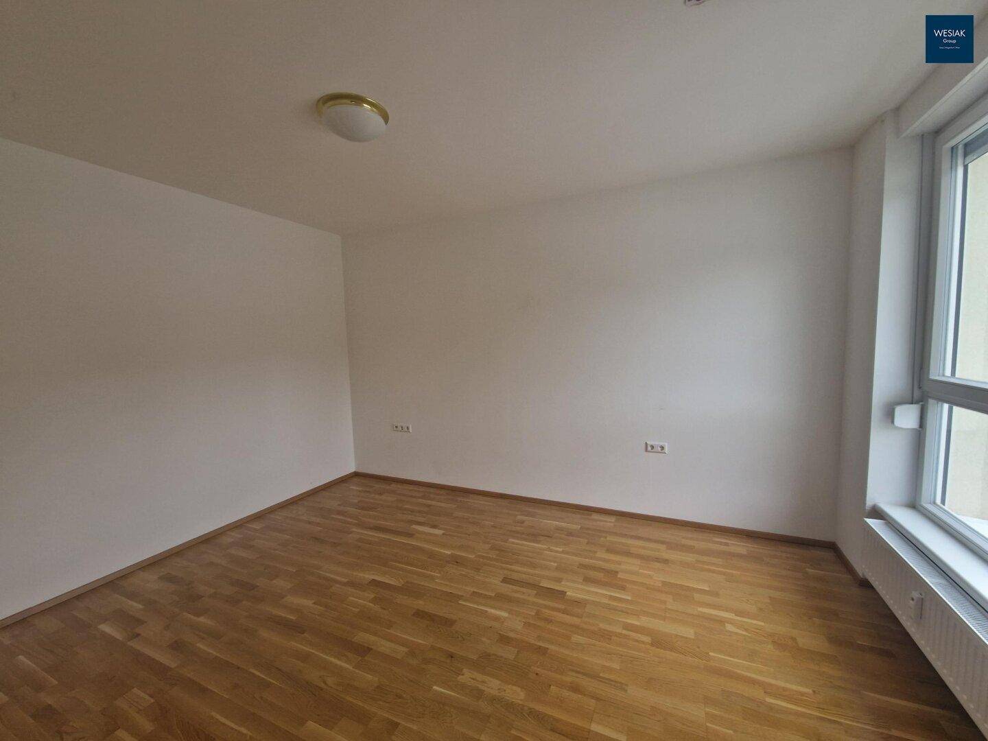 Helles Schlafzimmer mit Parkettboden, großen Fenstern und ausreichend Platz.